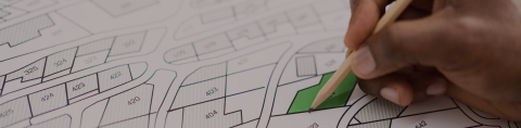 Map of neighborhood block with hand holding pencil coloring in the map